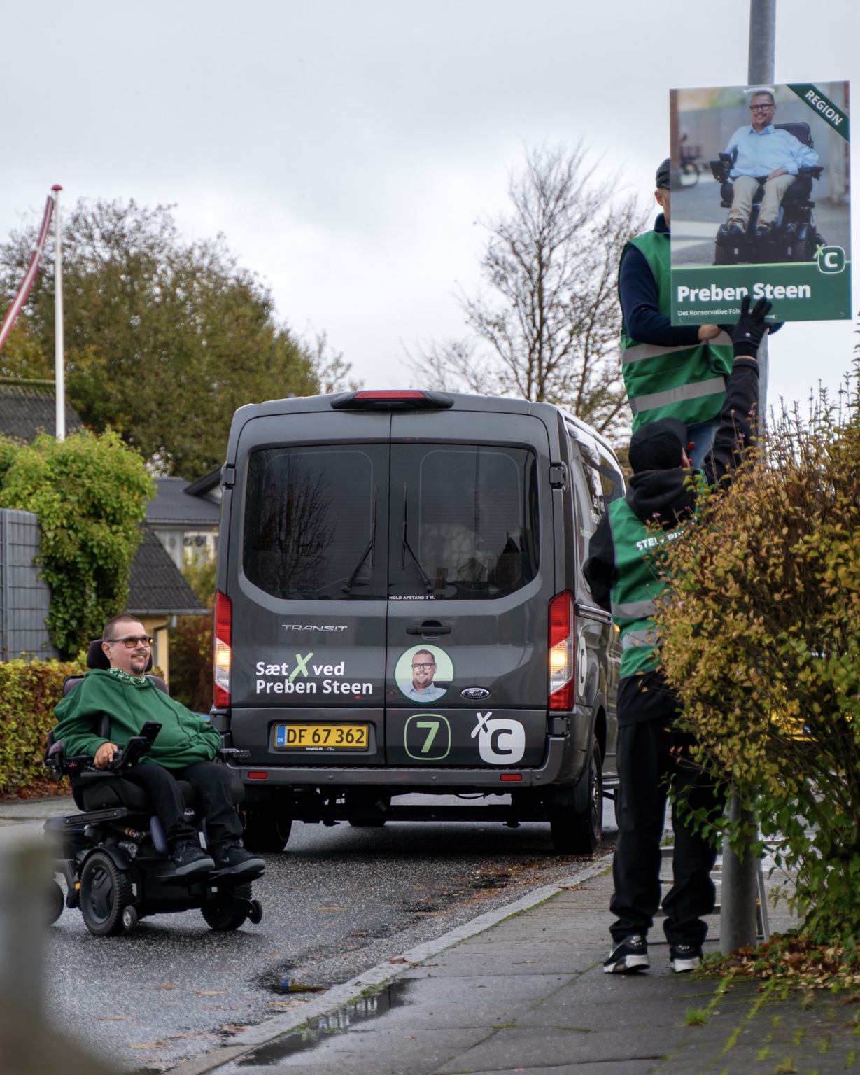Preben Steen i kørestol under valgkampen ved en kampagnebil og valgplakat